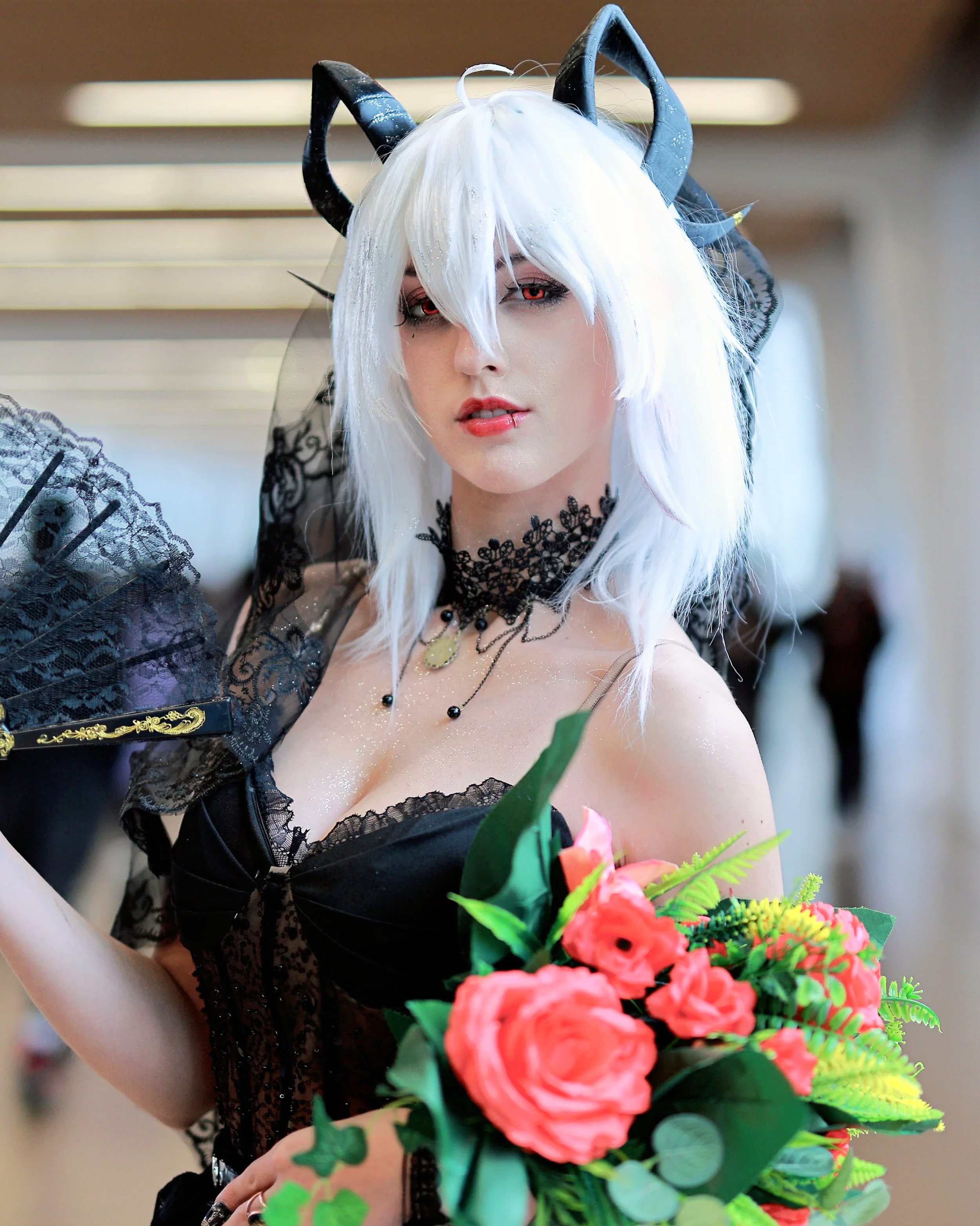 A woman dressed in cosplay with long white hair, black cat ears, black lace dress, black lace choker, and holding a bouquet of pink roses and green leaves. cosplayer gaming anime manga