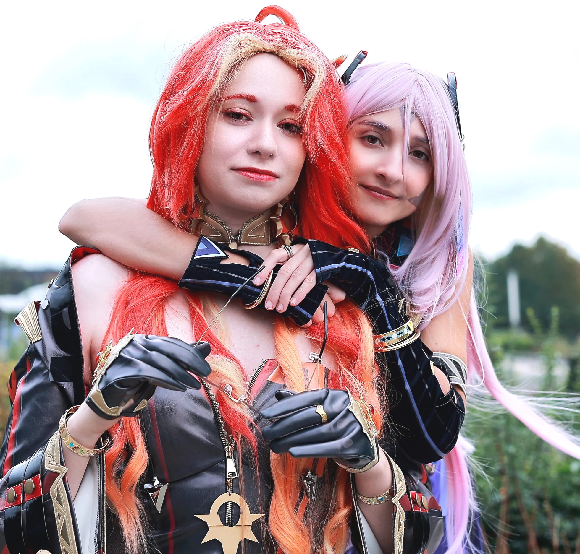 Two women in colorful, fantasy-style costumes embracing outdoors, with a blurred background of greenery. Cosplayer Cosplay anime manga gaming