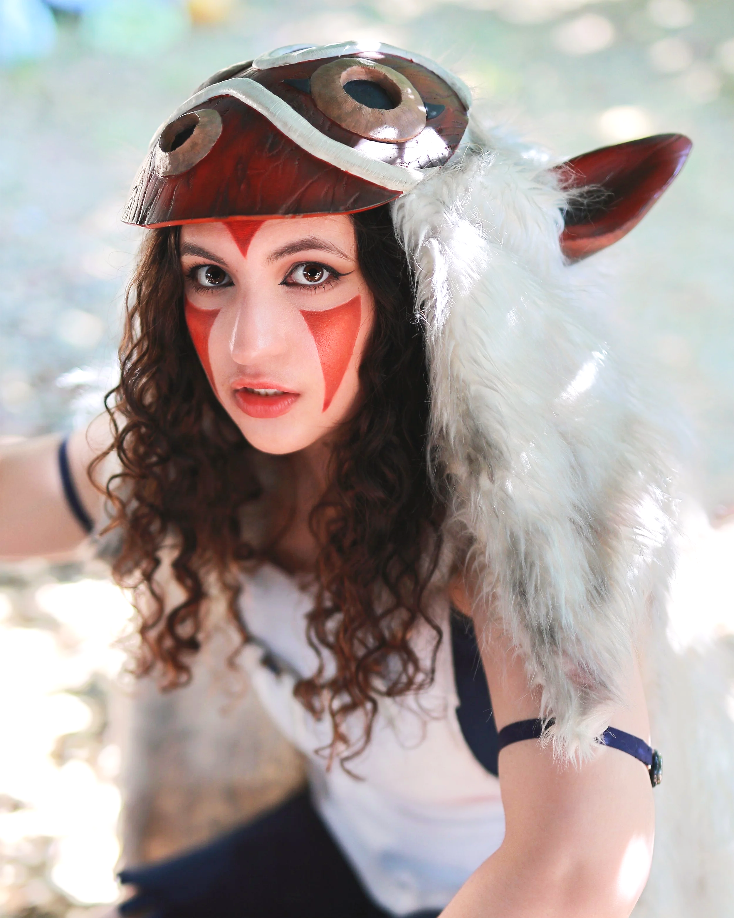 Woman in a costume with face paint, wearing a mask and a furry hat with animal ears. cosplay cosplayer mononoke anime manga