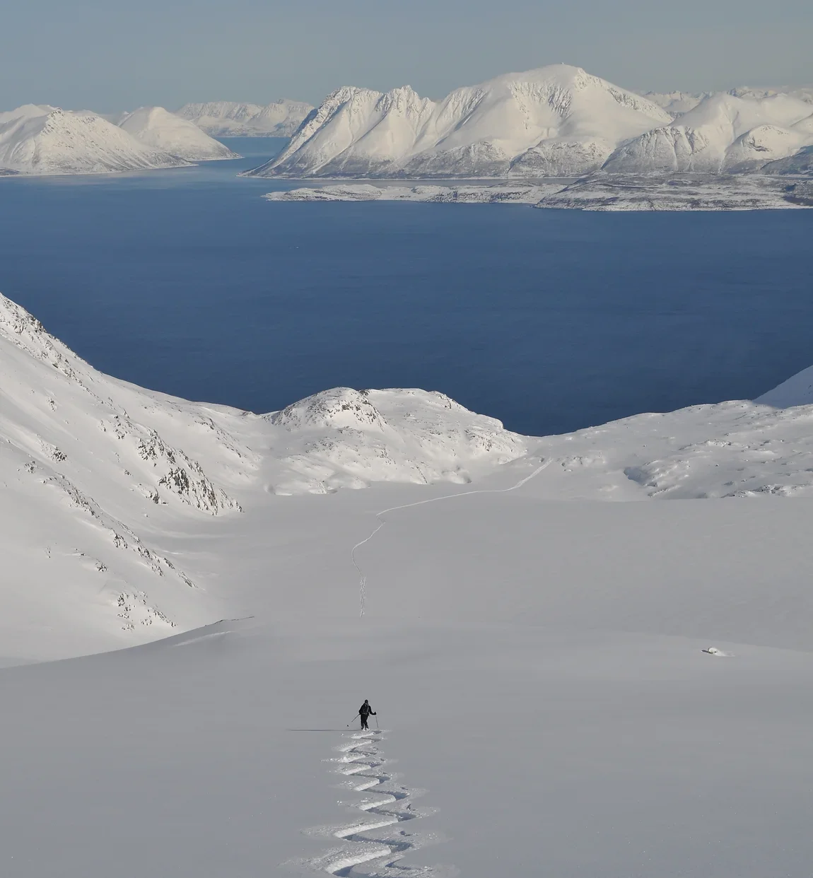 Skiing fresh powder down to a fjord in Norway