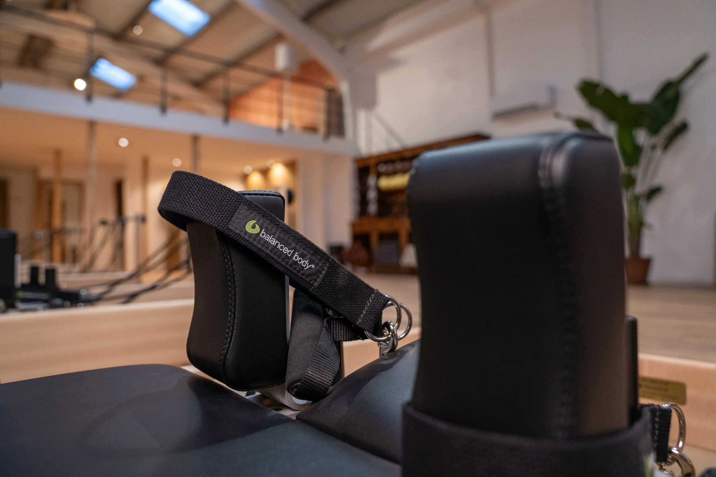 Photos qui contextualise une machine de Pilates reformer dans le studio de Pilates reformer Auréa, on y vois les accoudoir et les straps pour les mains avec l'inscription Balanced Body dessus. D'autre machines sont disposé derriere.
