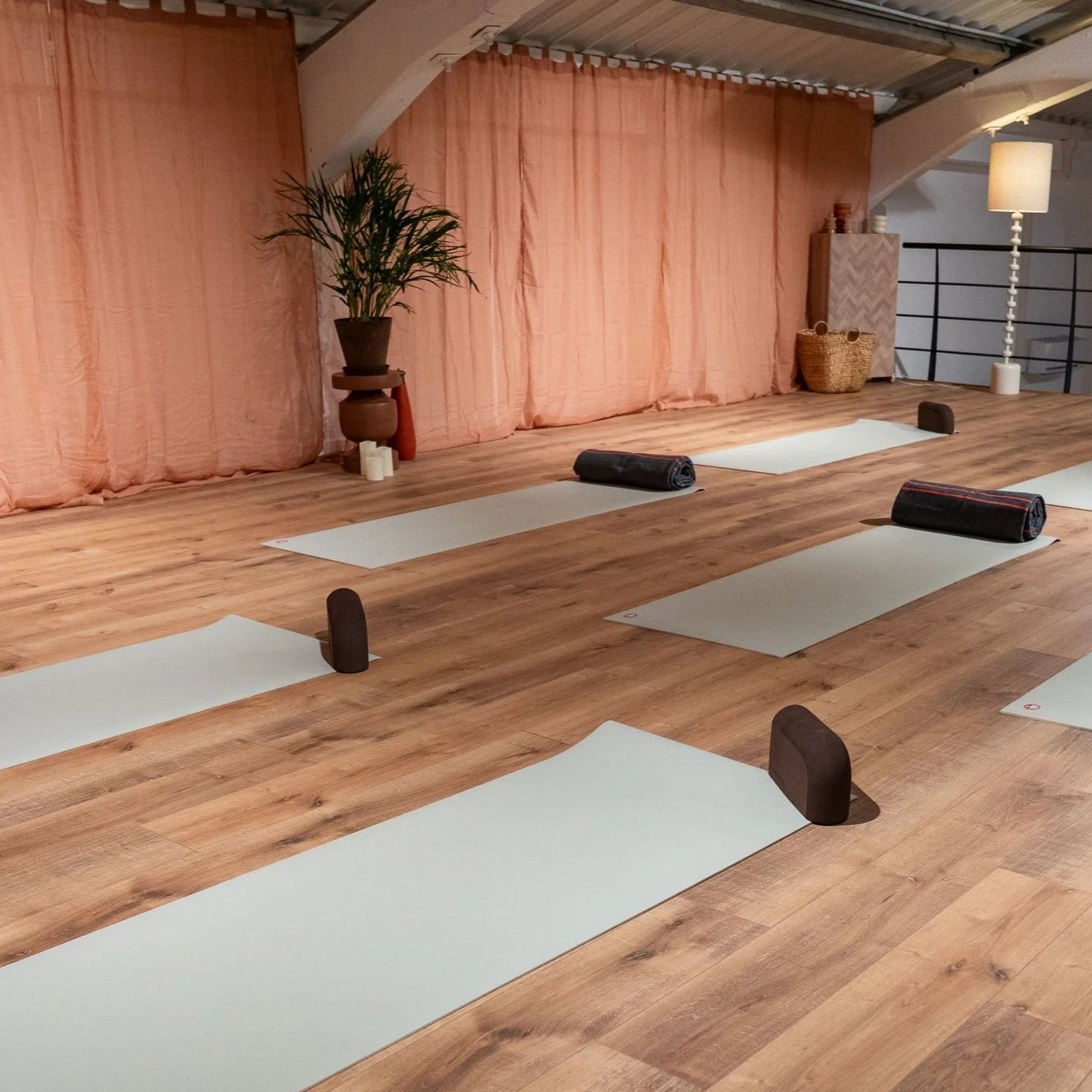 Tapis de Yoga Manduka disposé au sol avec des Yoga block et des couverture de Yoga dans un environnement chaleureux terracota