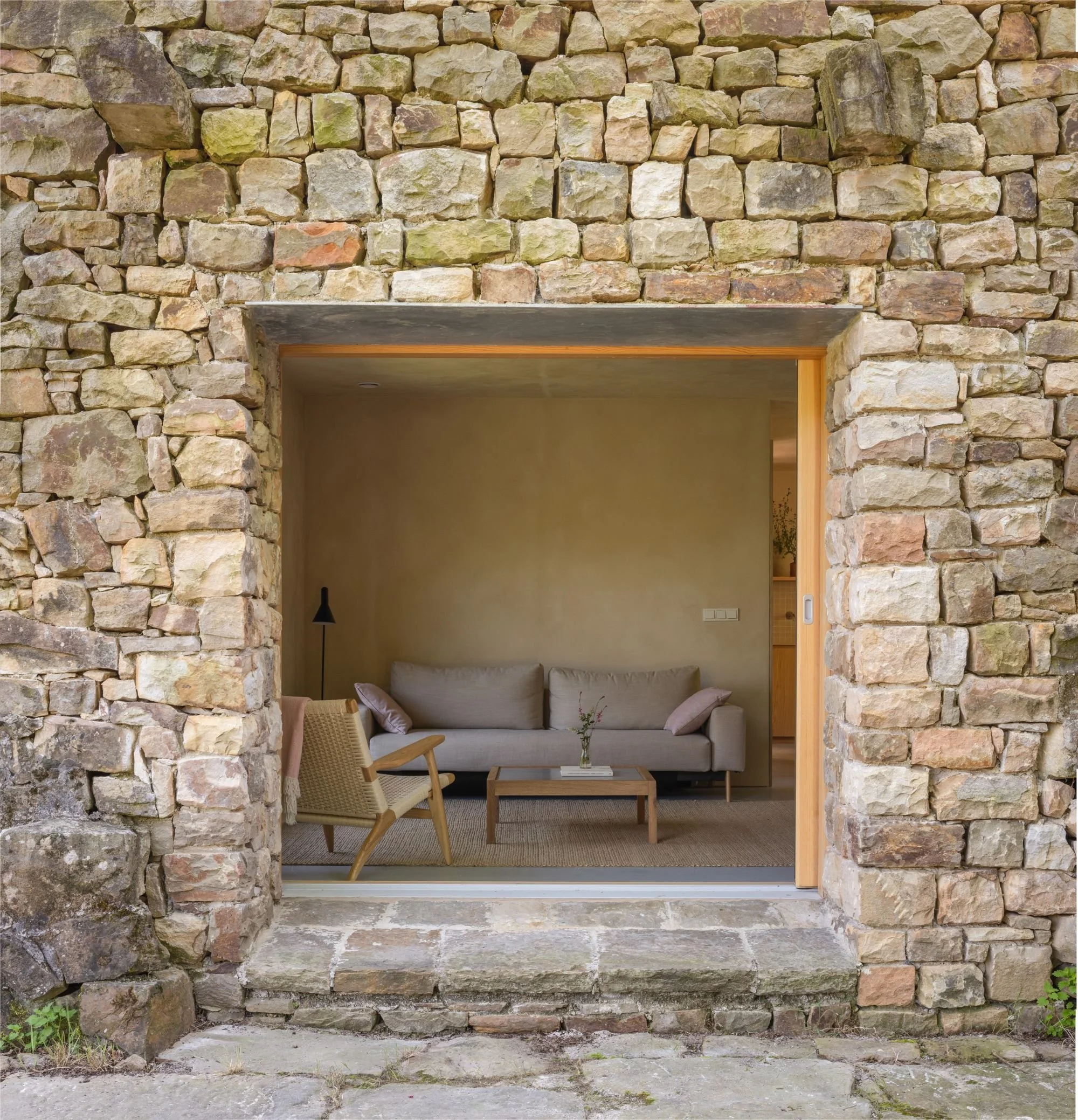 large window in a stone wall of a refurbished cabaña pasiega in cantabria. Minimal living room made of natural materials