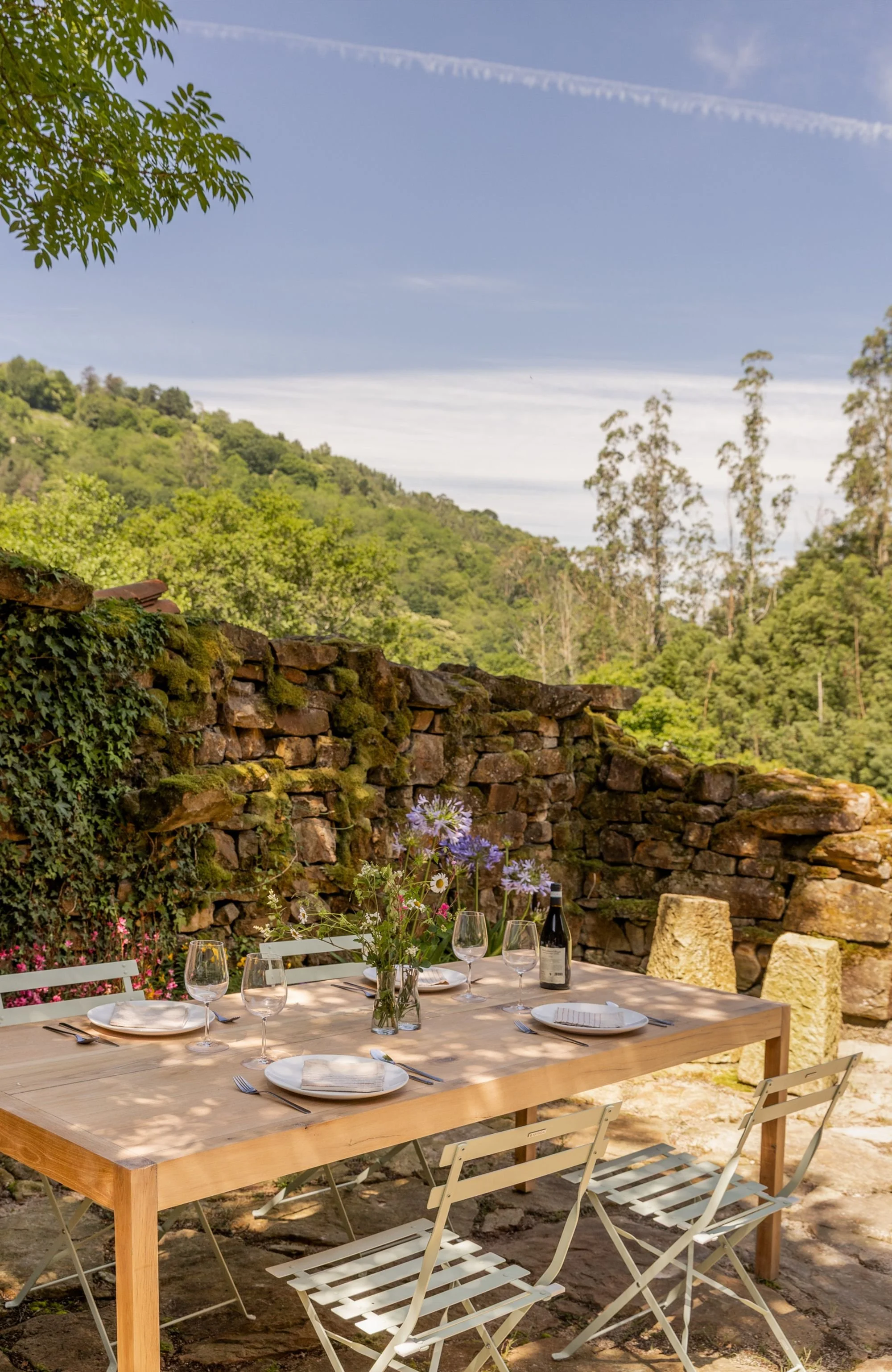 patio de piedra abierto al paisaje con mesa de madera