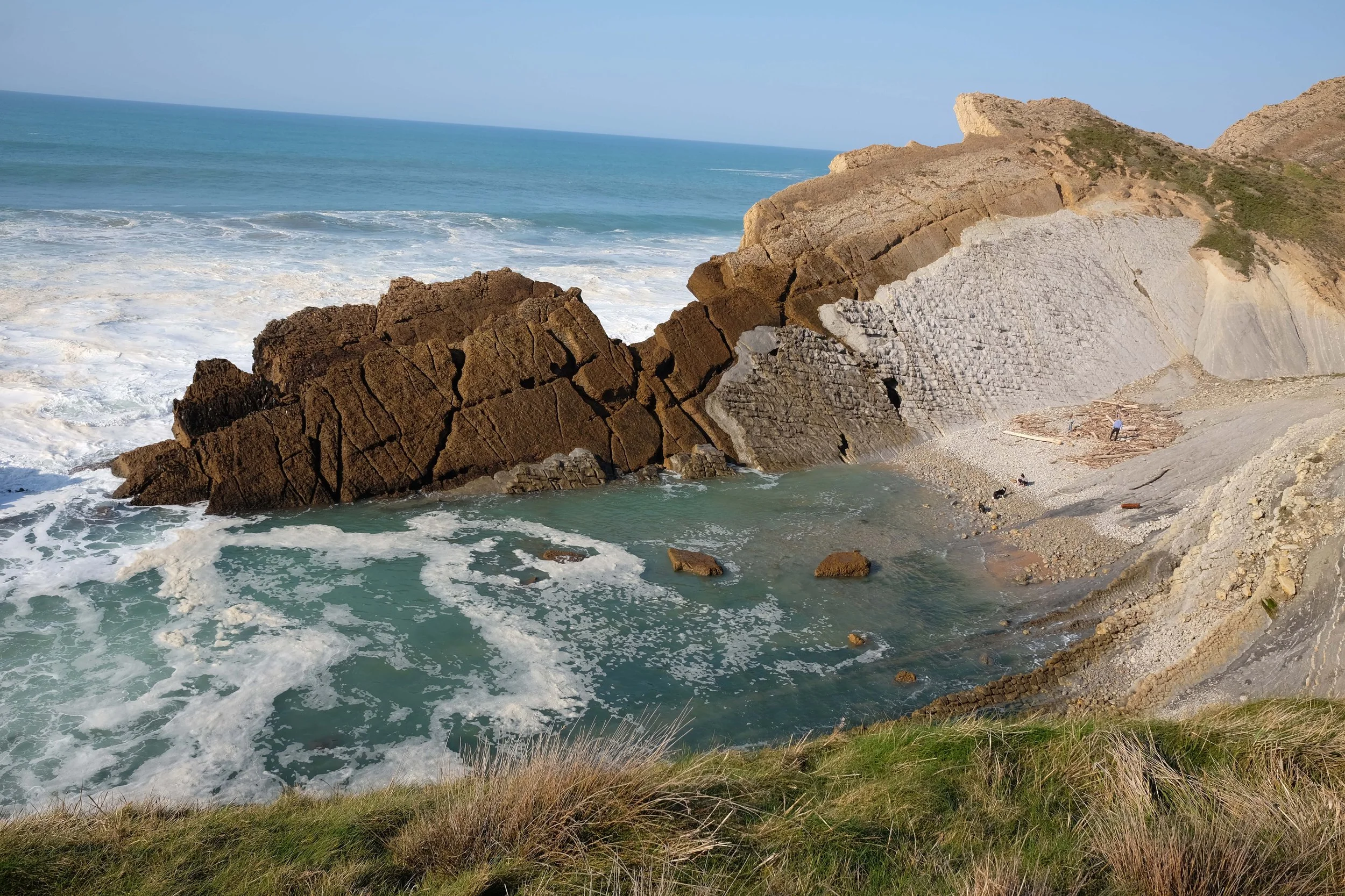 Costa rocosa con olas del mar rompiendo en la orilla, acantilados y formaciones rocosas en la playa en un día soleado.