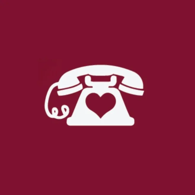 White vintage telephone with a heart shape in the center on a maroon background.