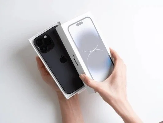 Person opening an iPhone 14 box with a screen protector included.