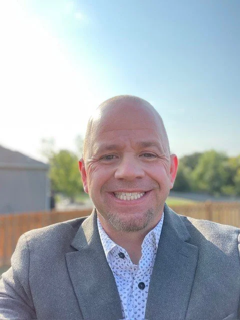 Silhouette of a person's head and shoulders, with short hair, facing forward.