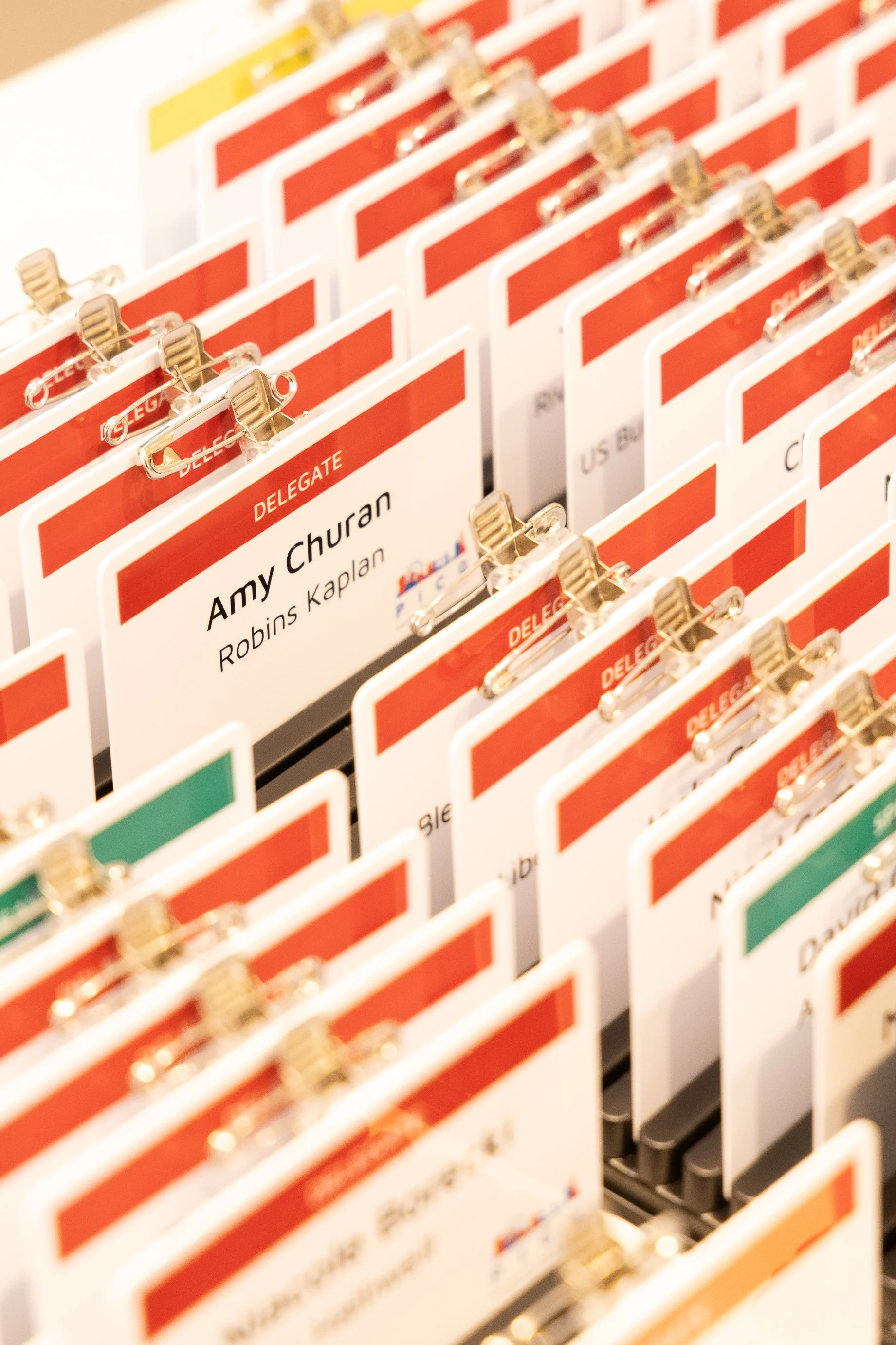 Conference name tags on a display rack, with one tag reading 'Amy Churan' and 'Robins Kaplan'.