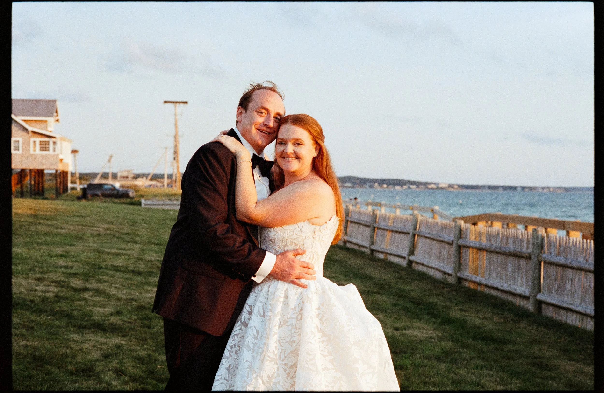 Lindsey and Andrew are embracing each other on their special day, posed on their family's property on Cape Cod.