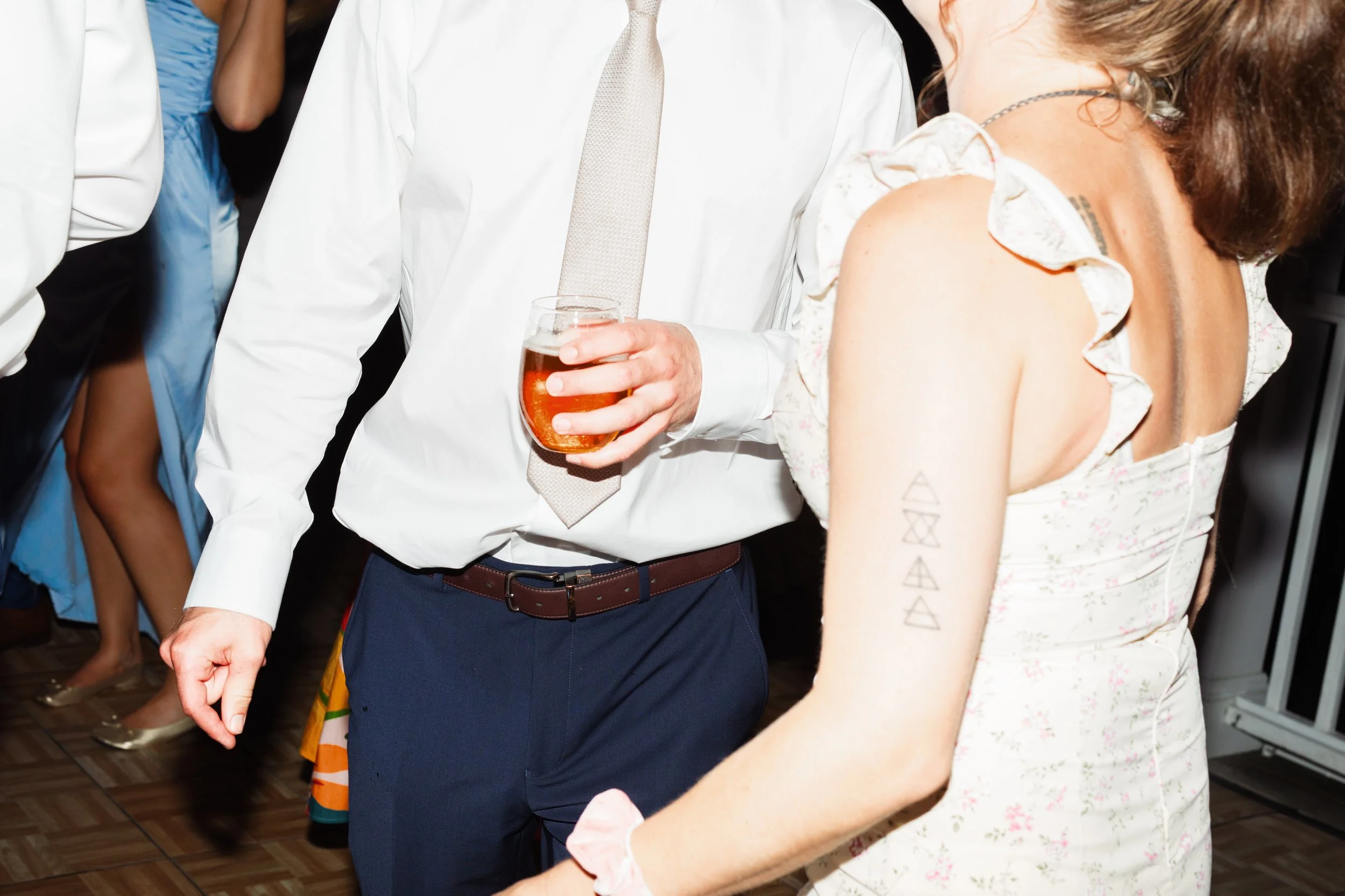 Guests dance together while holding drinks.