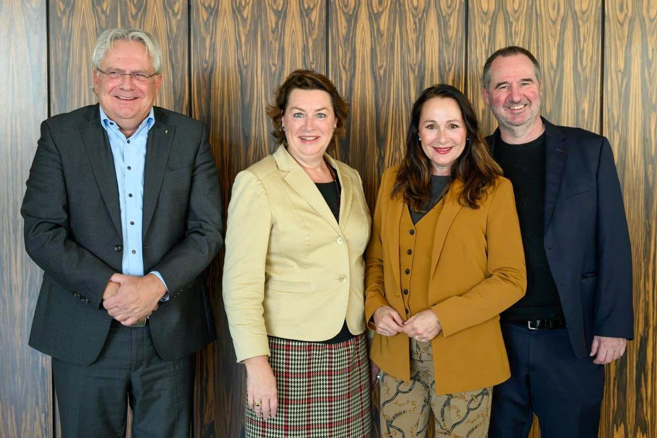 Vorstand der Kölner Offenbach-Gesellschaft e.V. 2025: Gruppenfoto mit vier Vorstandsmitgliedern vor Holzstruktur