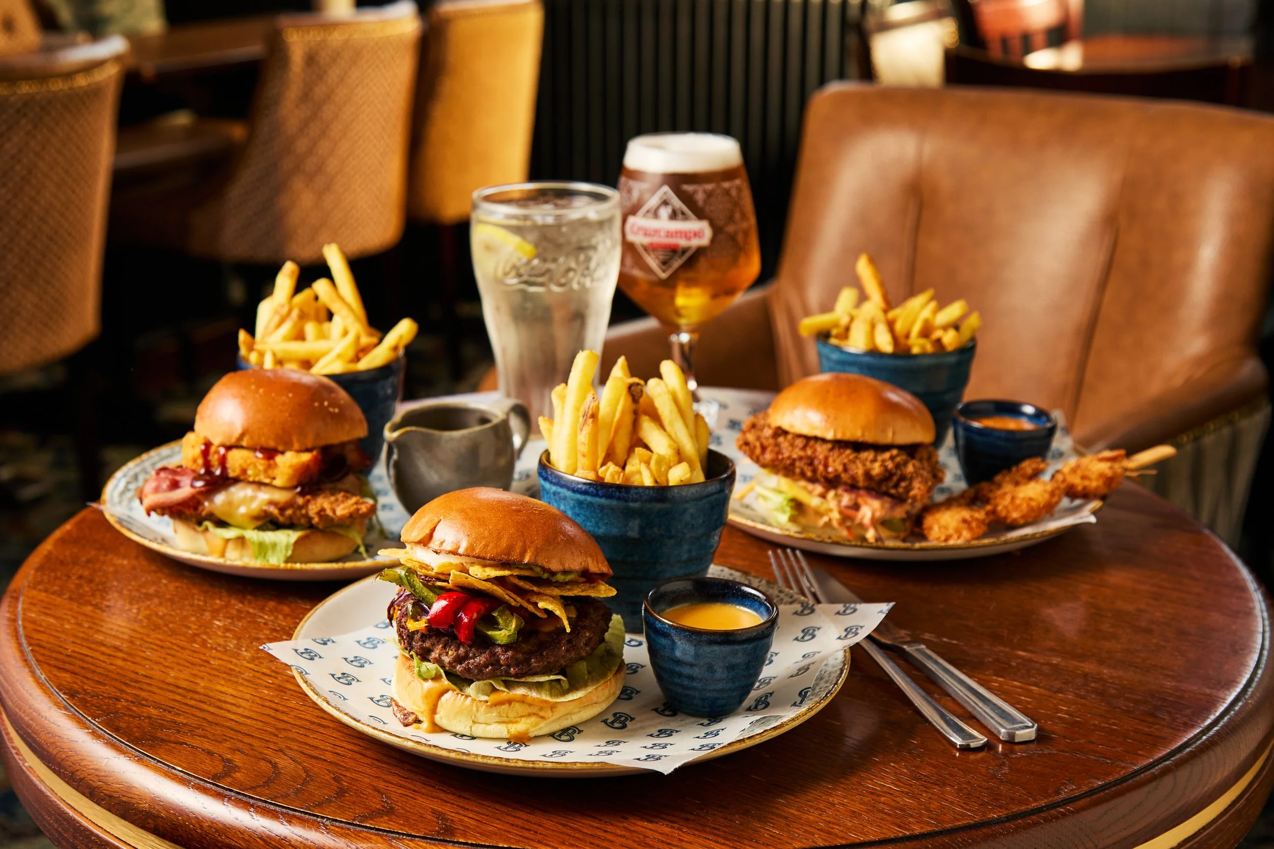 A table with several sliders, French fries, and drinks in a restaurant setting.