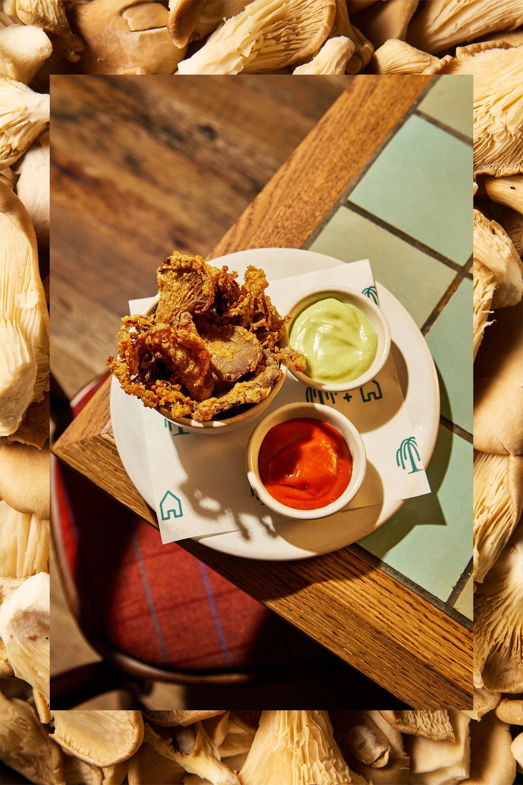 Fried chicken wings served with green and red dipping sauces on a white plate at a restaurant.