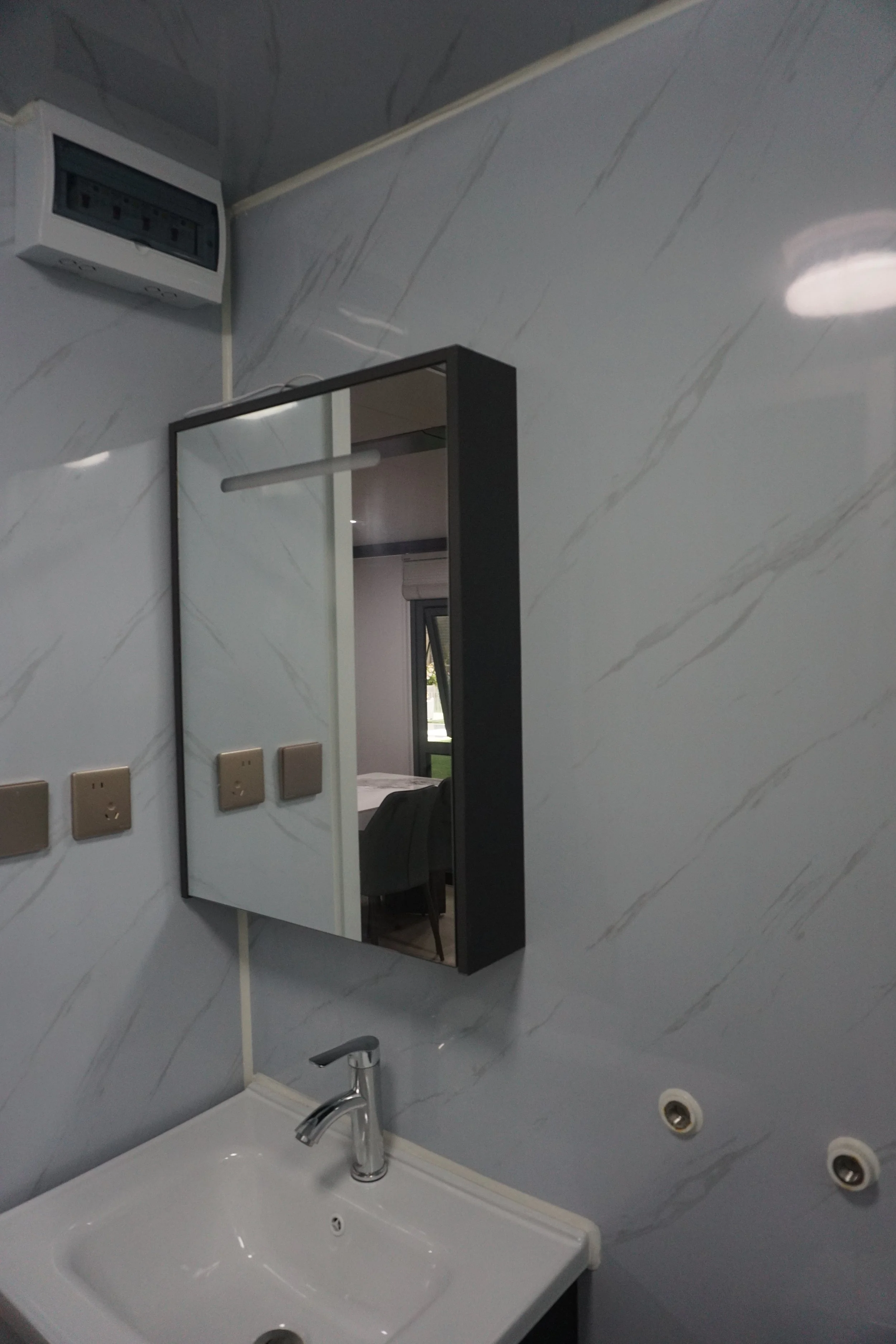 Bathroom with marble wall, mirror cabinet, white sink, chrome faucet, electrical outlets, and visible ac unit.