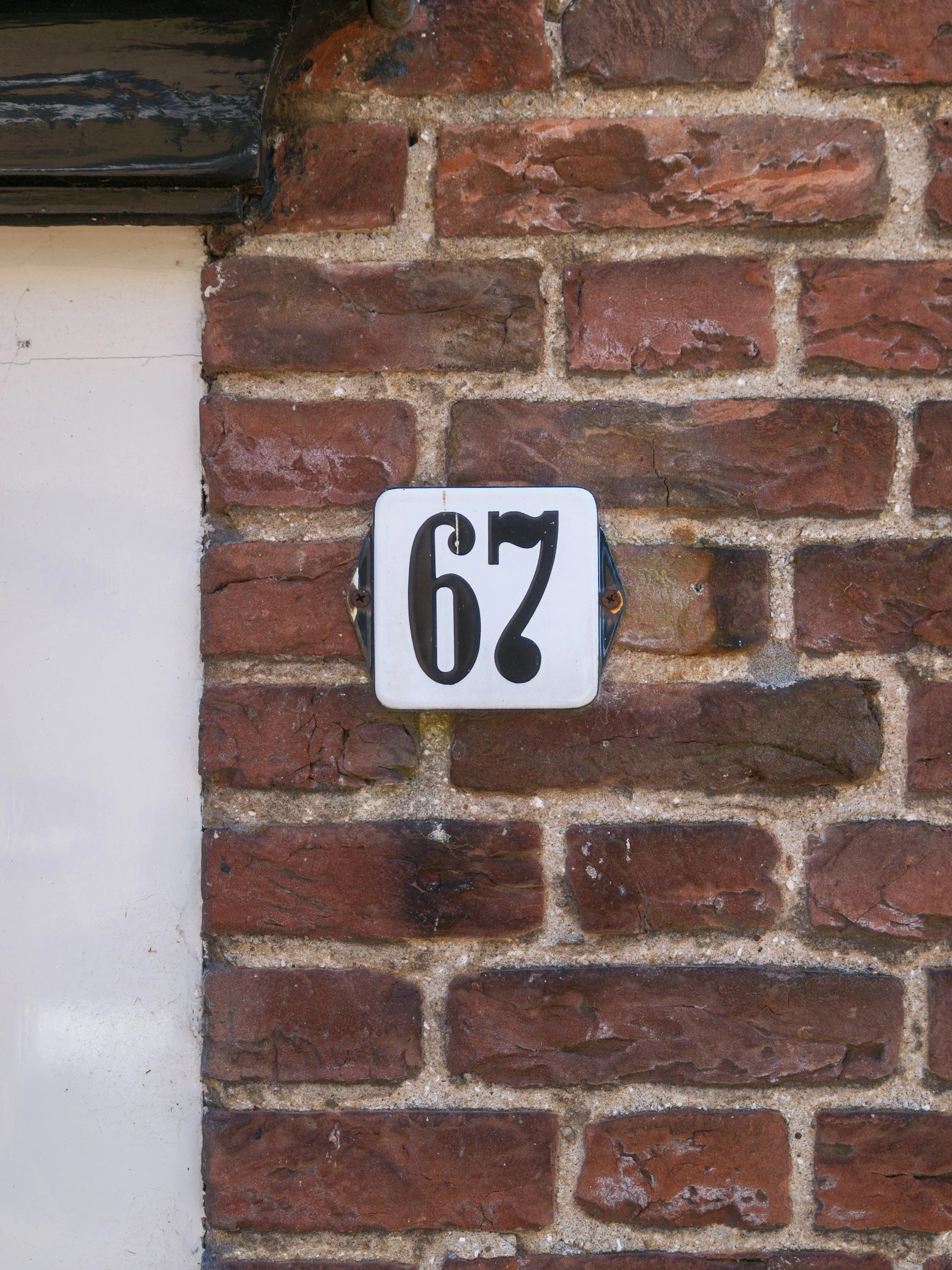 House number 67 on a brick wall symbolising the viral 6/7 trend and how PDA children are labelled as difficult rather than dysregulated.