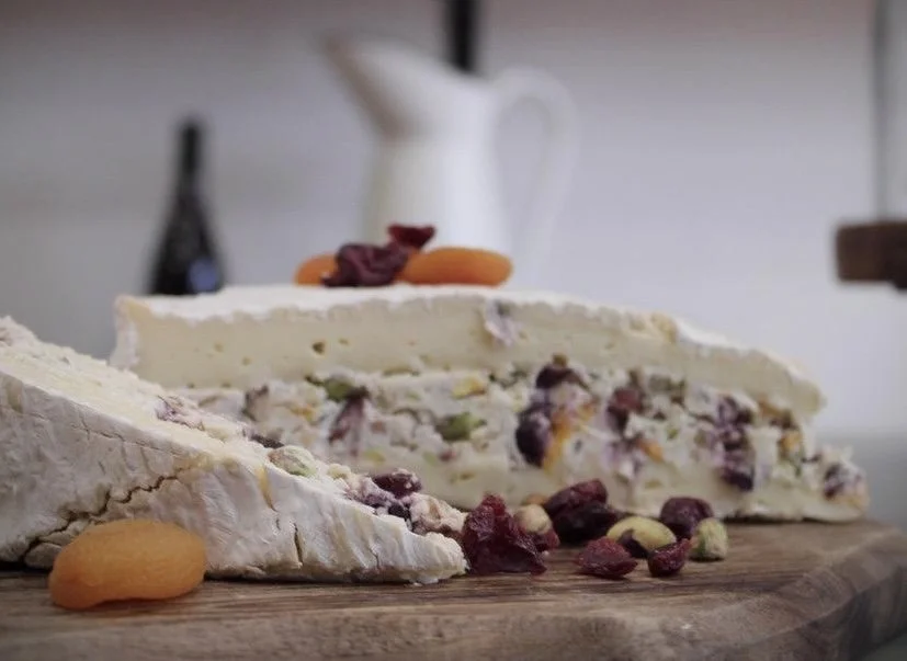 Gâteau de fromage avec des fruits secs et des fruits frais, sur une planche en bois.