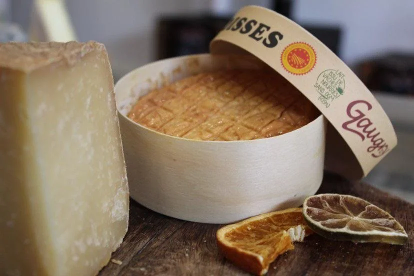 Fromage à pâte dure, fromage en croûte, tranches d'orange séchée, et un fromage en cercle avec une étiquette