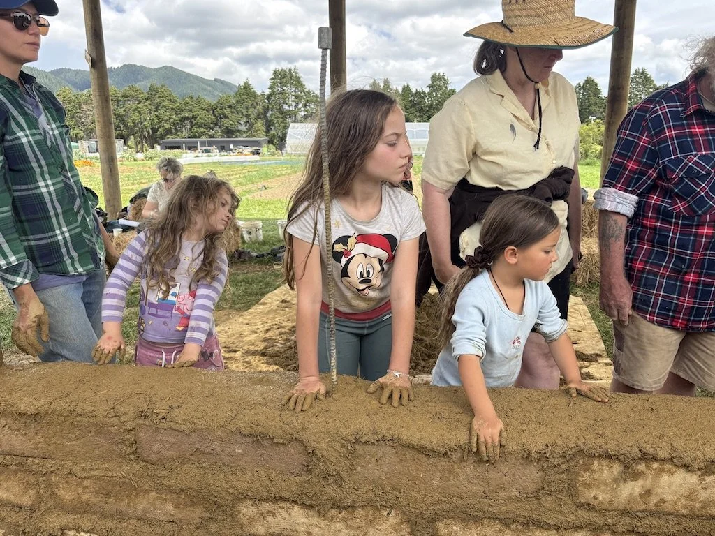 Earth School Aotearoa children building an earthen wall with adobe bricks at a Sigi Koko workshop in Aotearoa, New Zealand.
