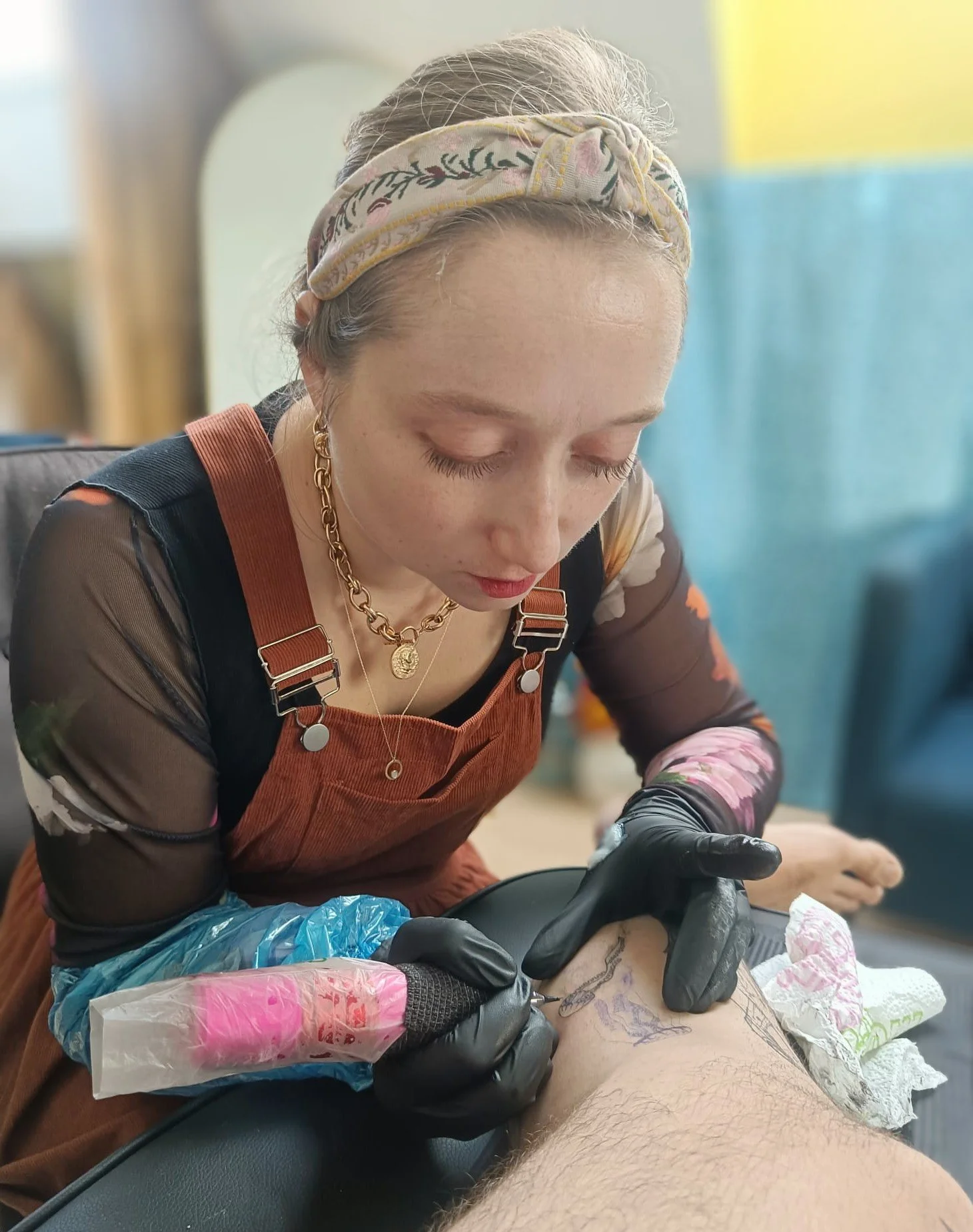 Een vrouw krijgt een tattoo gezet op haar bovenbeen door een tattoeëerder.