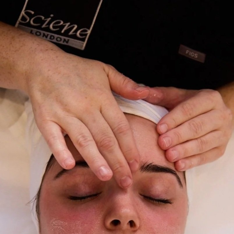 A man receiving a massage on his neck and shoulders while lying face-up with eyes closed.