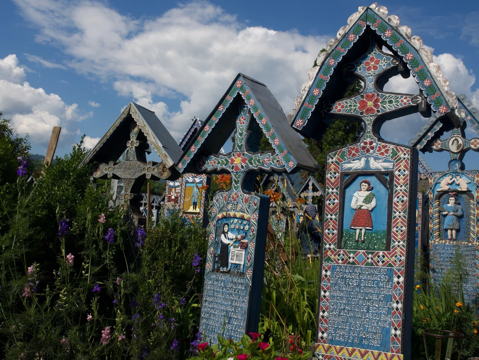 Los cementerios rumanos no son lugares de muerte, sino paisajes vivos. All&iacute; descansan historias que a&uacute;n conversan con el viento: cruces de madera tallada, flores frescas junto a retratos esmaltados, colores que desaf&iacute;an el gris d