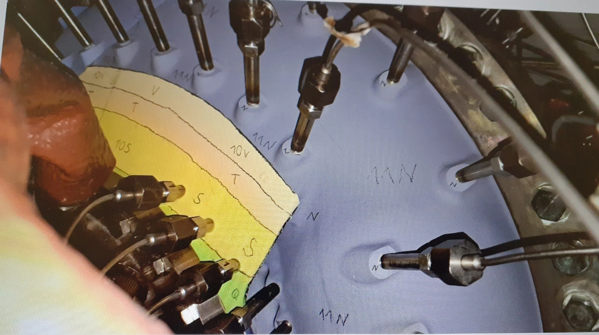 Close-up view of a turbomachine blade casing, showing various sections with different thermal paints and various tubing and wiring components.
