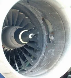 Close-up of a jet engine turbine with visible blades and central shaft, with a broken blade in the structure.