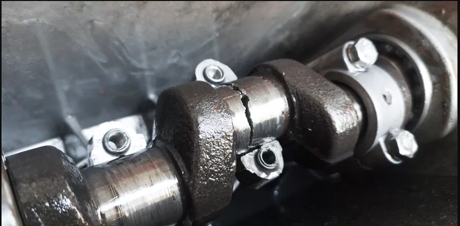 Close-up of an engine crankshaft with visible cracks and bolts.