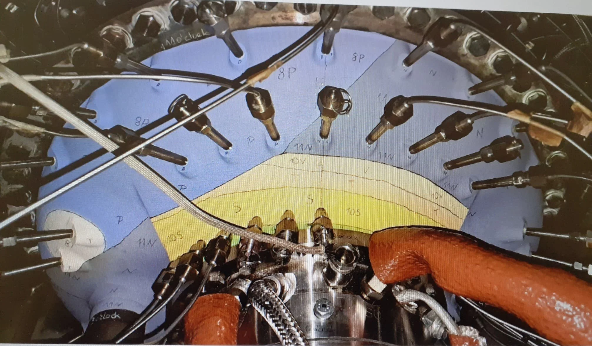 Close-up view of a turbomachine blade casing, showing various sections with different thermal paints and various tubing and wiring components.