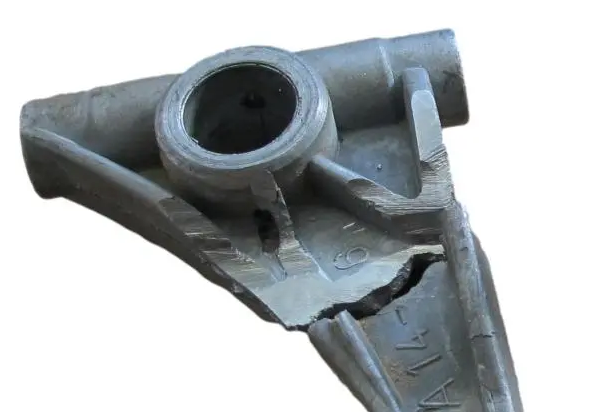 A metal car engine part with a circular opening and several connecting arms.