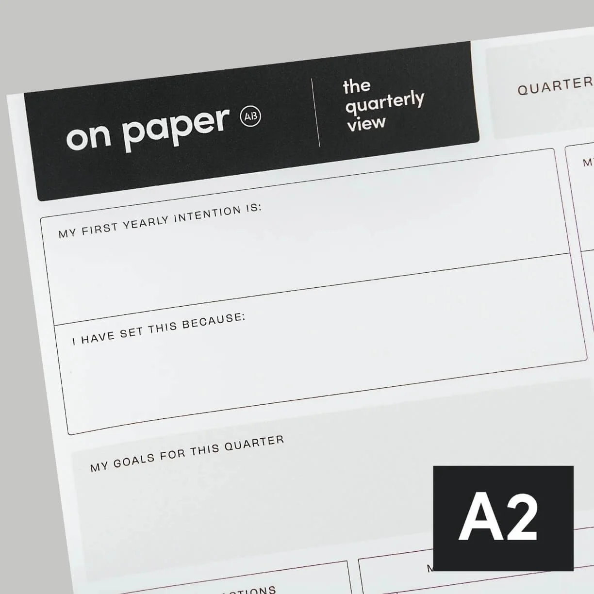 A partially visible planner or worksheet titled "on paper the quarterly view" with sections for goal setting and intentions, on a light grey background.