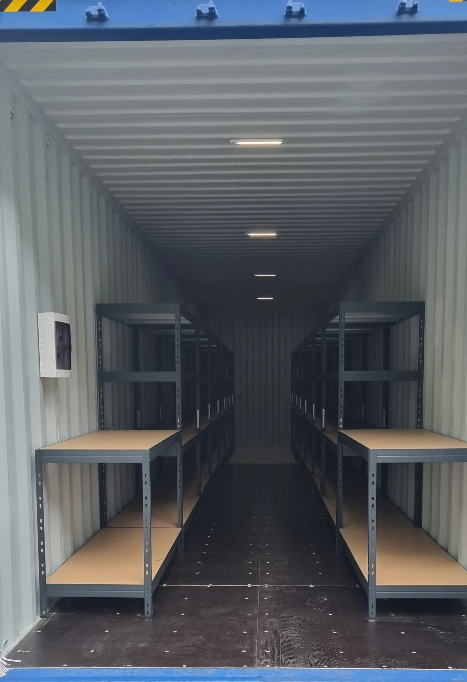 Empty storage unit with metal shelving units and wood shelves inside.