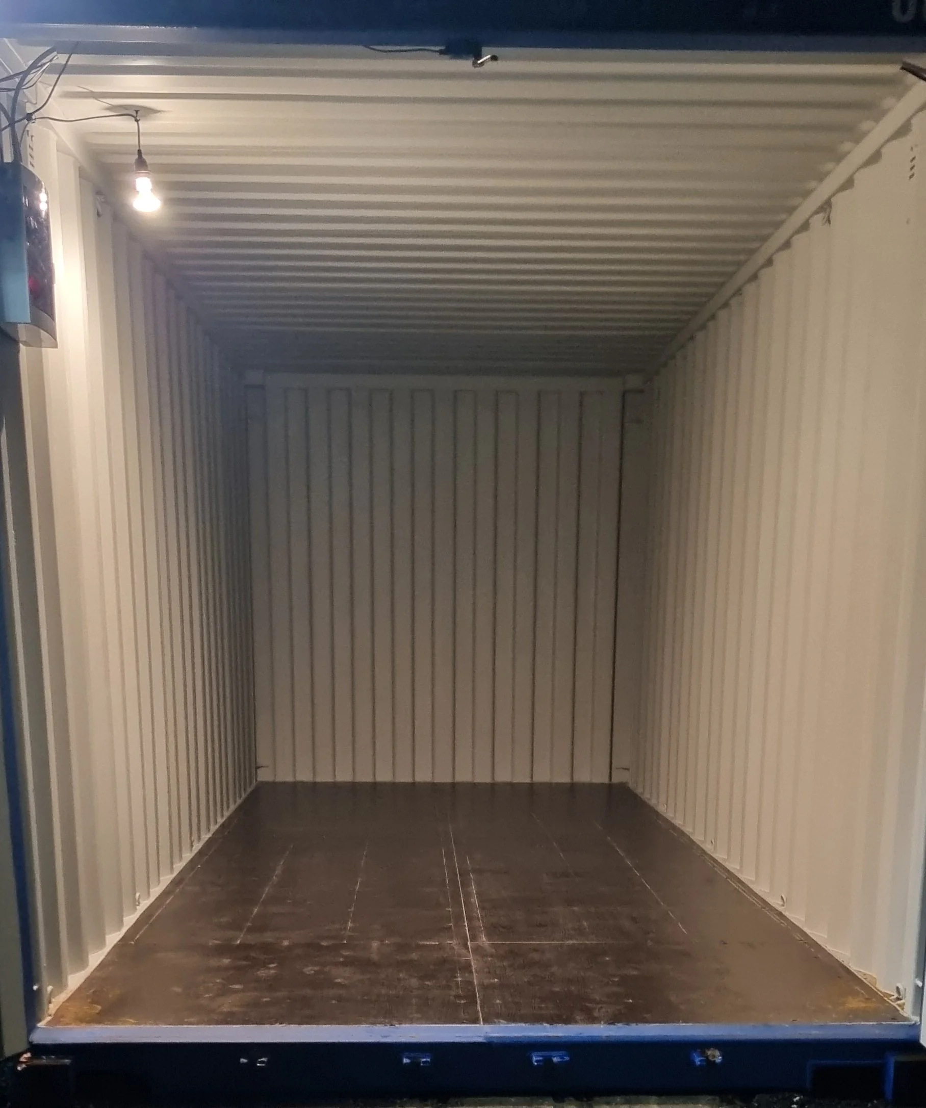 Empty cargo shipping container with beige metal walls and dark floor.