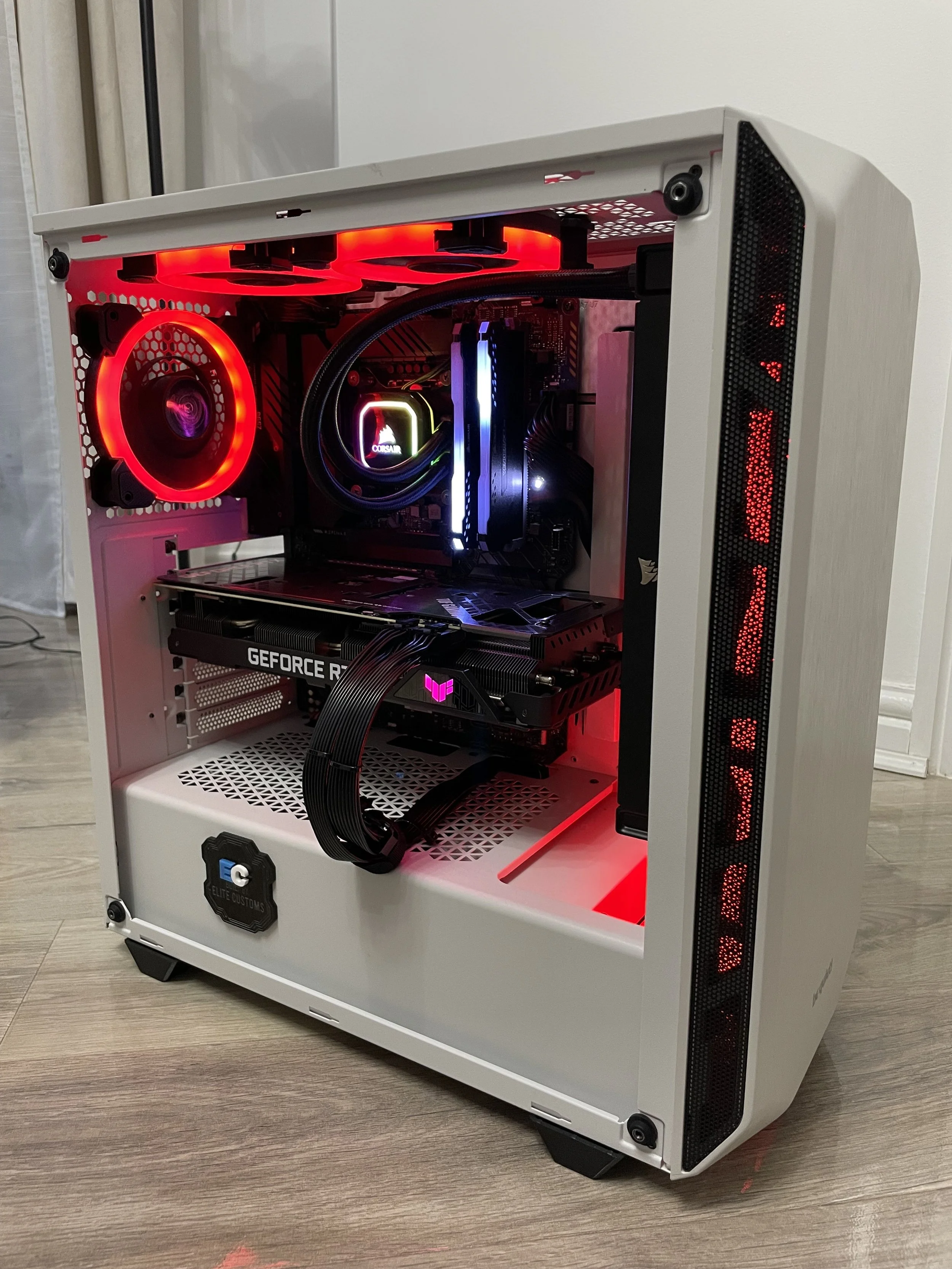 White gaming PC case with transparent side panel showing internal components, including a graphics card, CPU cooler, fans with red and blue LED lighting, and a motherboard.