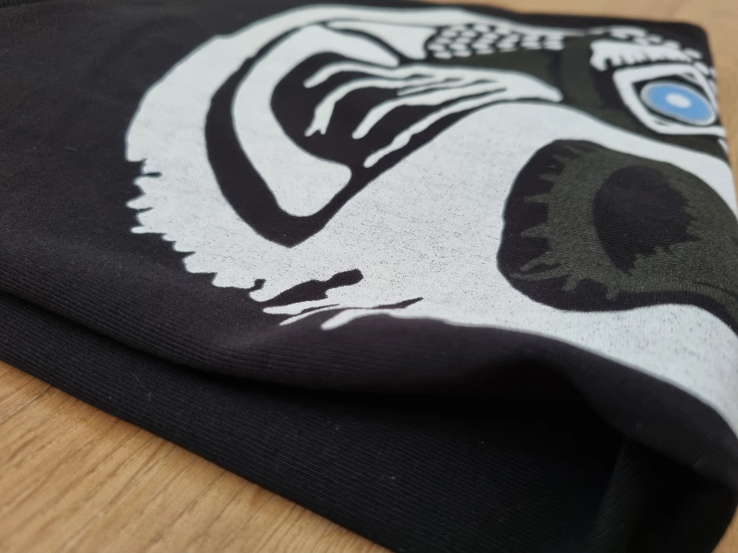 Close-up of a black Mongrel Logic T-shirt showing the Tenet artwork printed on organic cotton.