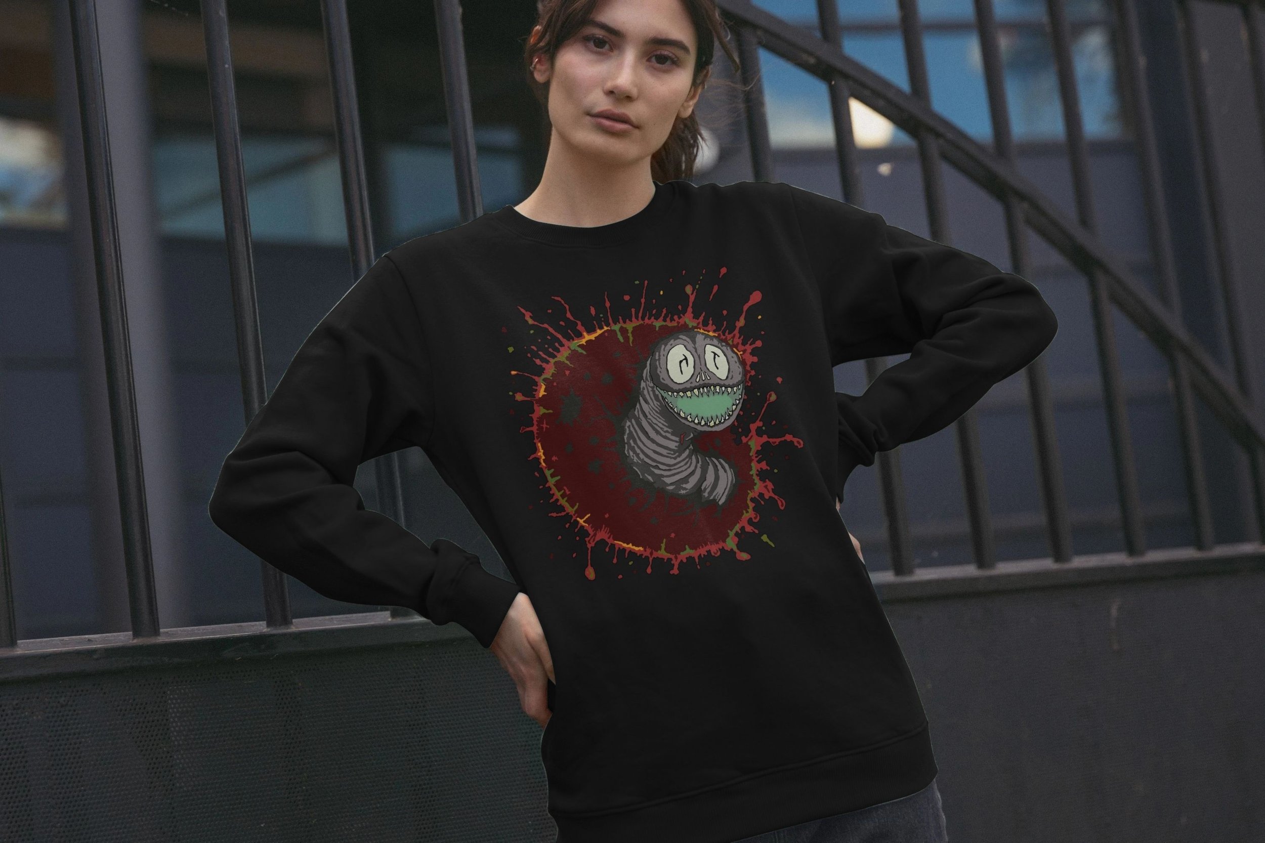Model wearing the Sun Eater II by Mongrel Logic in Black. Featuring a hand-drawn smiling grey cosmic worm, known as the Sun Eater, emerging from a deep red dying star surrounded by expressive paint splatters.