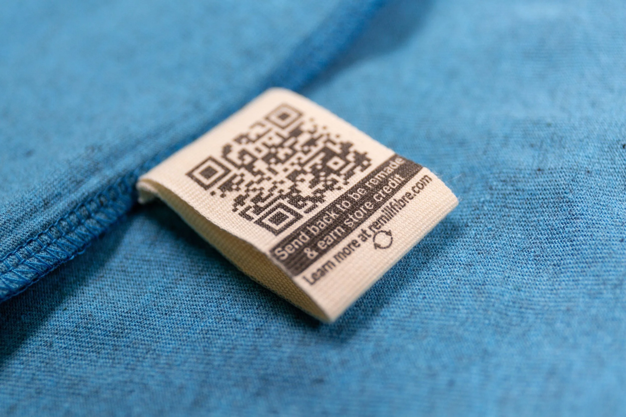 Remill QR return label inside a circular organic cotton garment, used to return worn clothing for remaking.