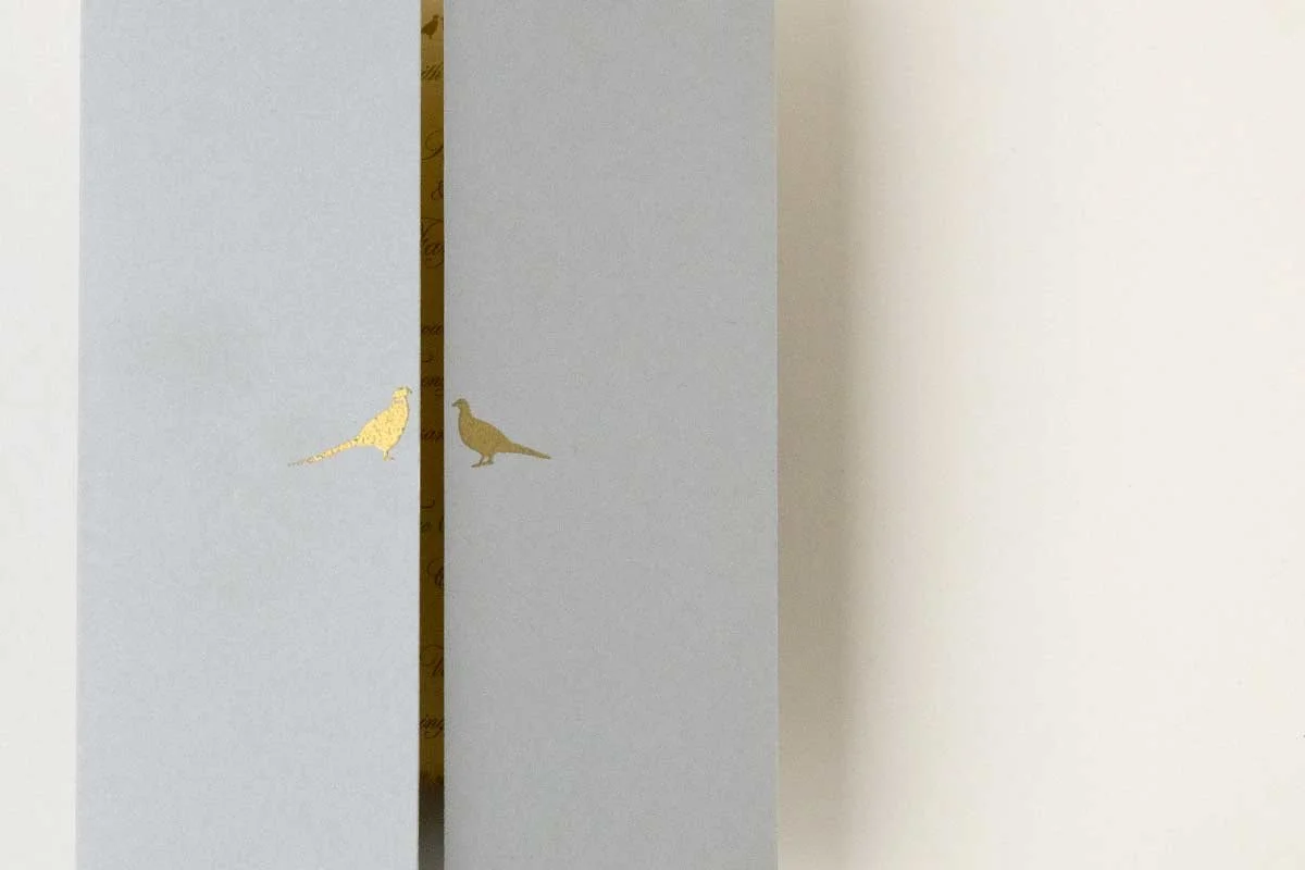 A white cabinet door with gold bird decals, slightly ajar, revealing a glimpse of the interior.