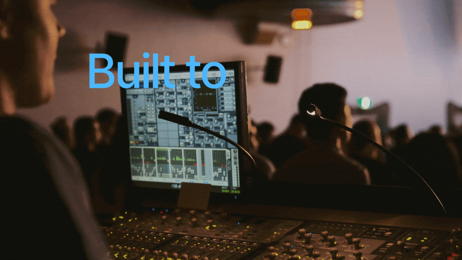 An audio mixing console in a darkened room.