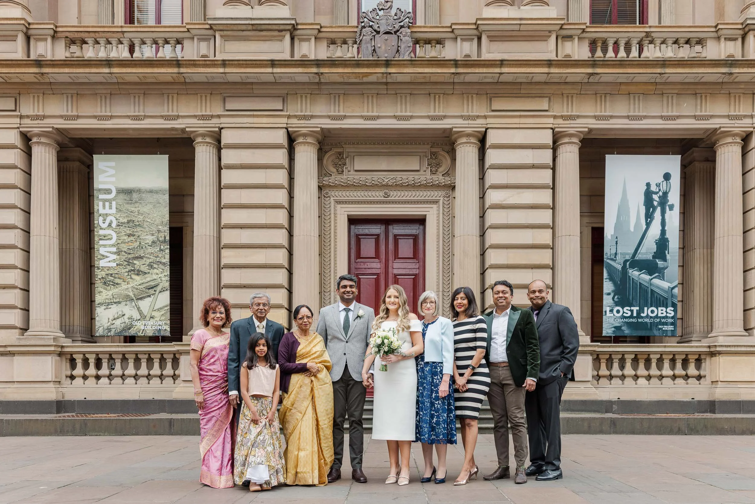 Melbourne civil registry wedding Old Treasury Building family portrait outside the historic entrance with newlyweds and guests gathered together.