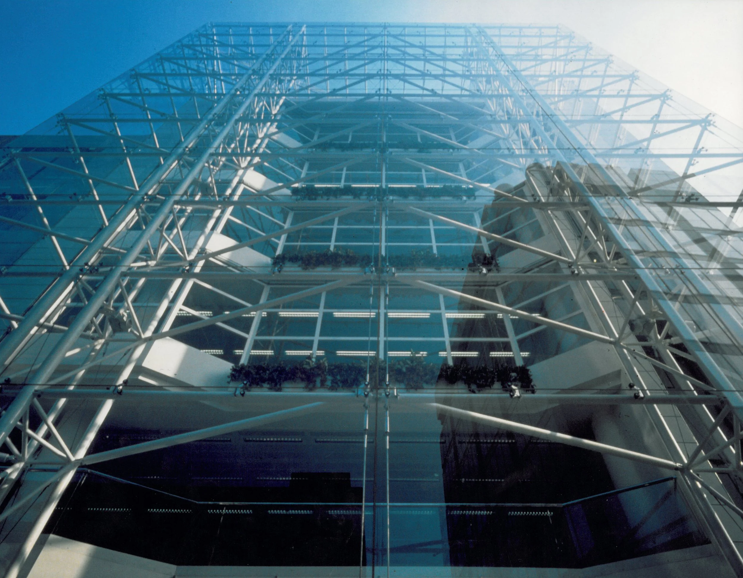 Ellis-Miller and Partners — A tall modern glass building with a visible steel framework from below, looking upward.