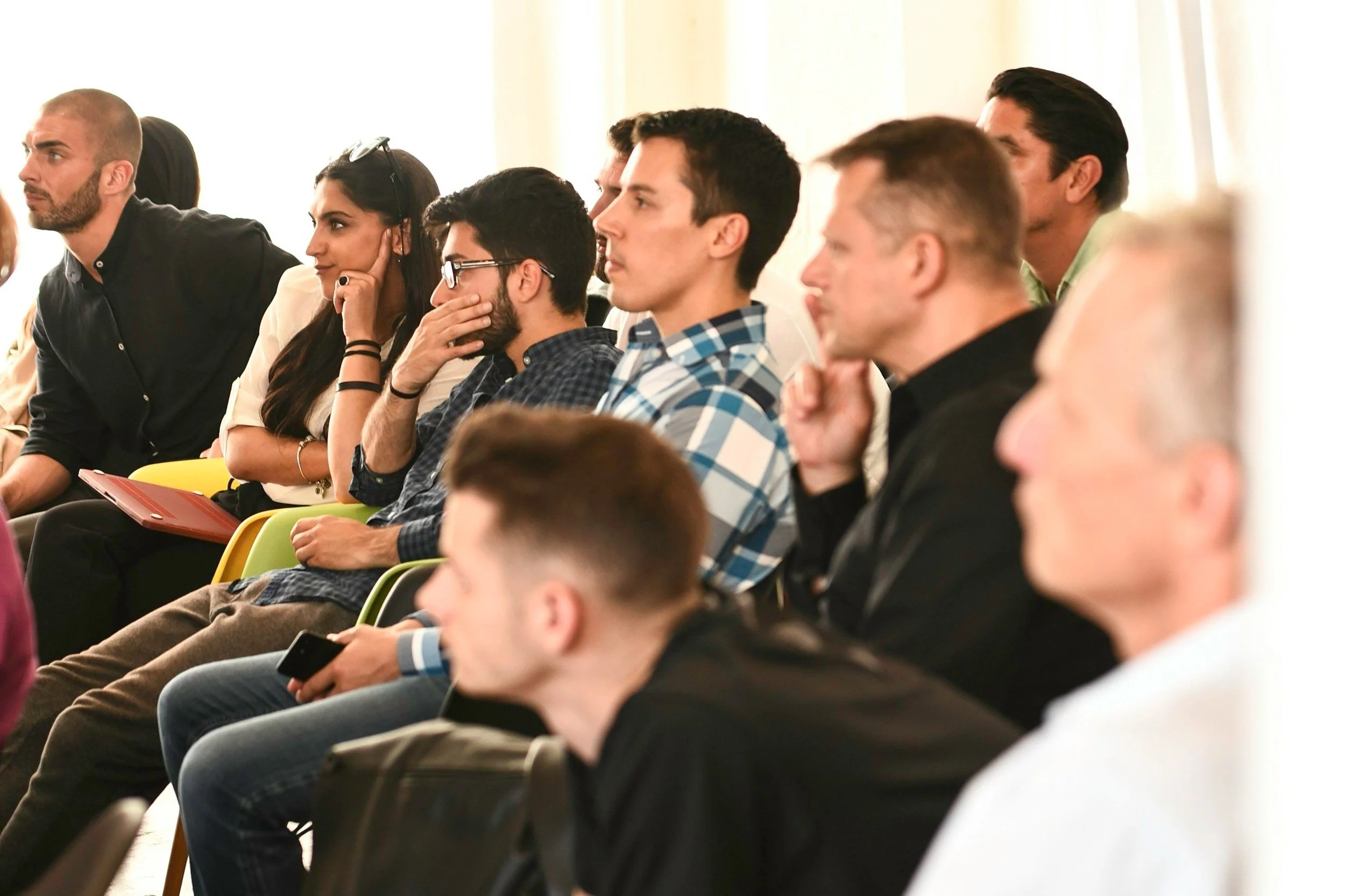 Menschen sitzen in einem Konferenzraum und hören aufmerksam einem Vortrag zu.