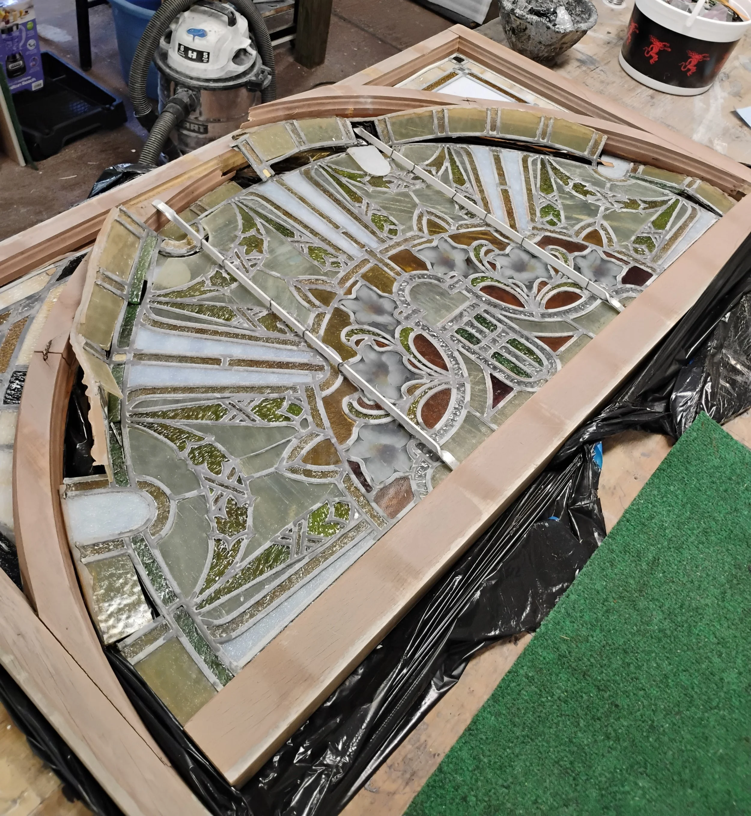 Photo of antique floral semi-circle stained glass panel with broken borders and frame