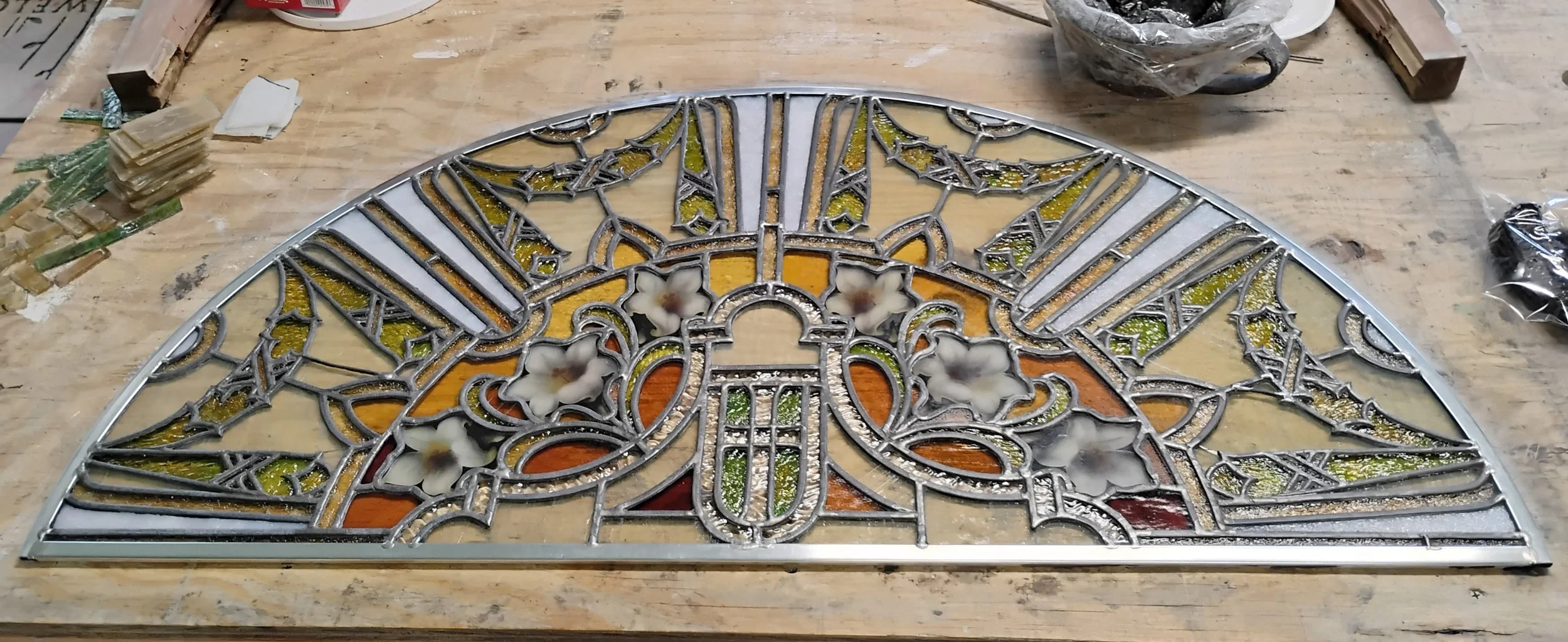 Photo of antique semi-circle floral stained glass panel after repairs have been made for a residential client.