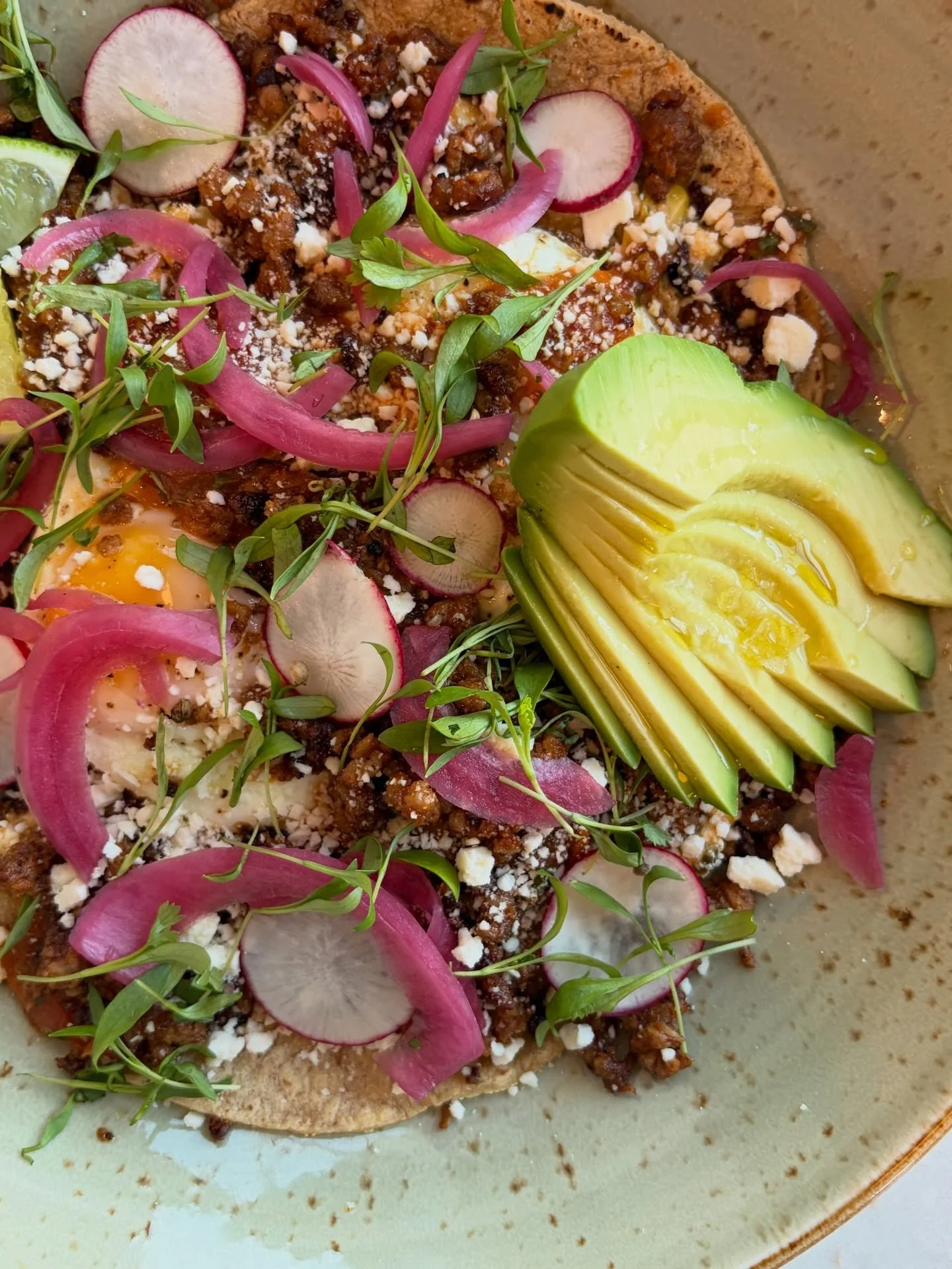 Our huevos rancheros start with local eggs from @highspirehillsfarm cooked sunny side up and set over corn tortillas with chorizo, our housemade ranchero sauce, and a street corn blend. 

Then come the layers: creamy avocado, salty cotija, bright pic