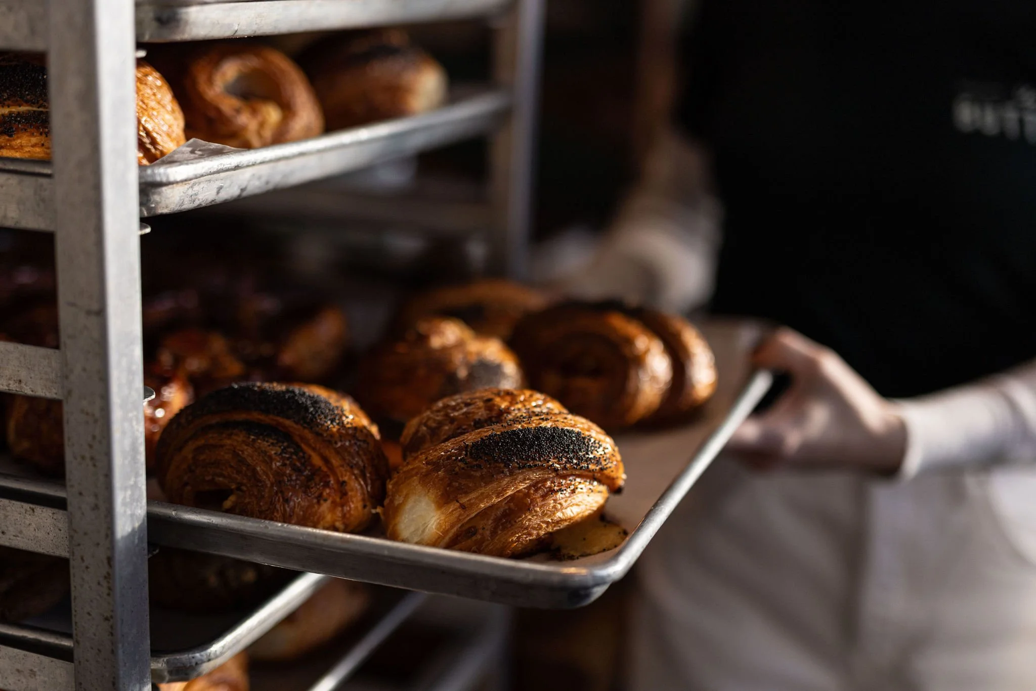 Close-up of freshly baked croissants with poppy seeds on a baking tray