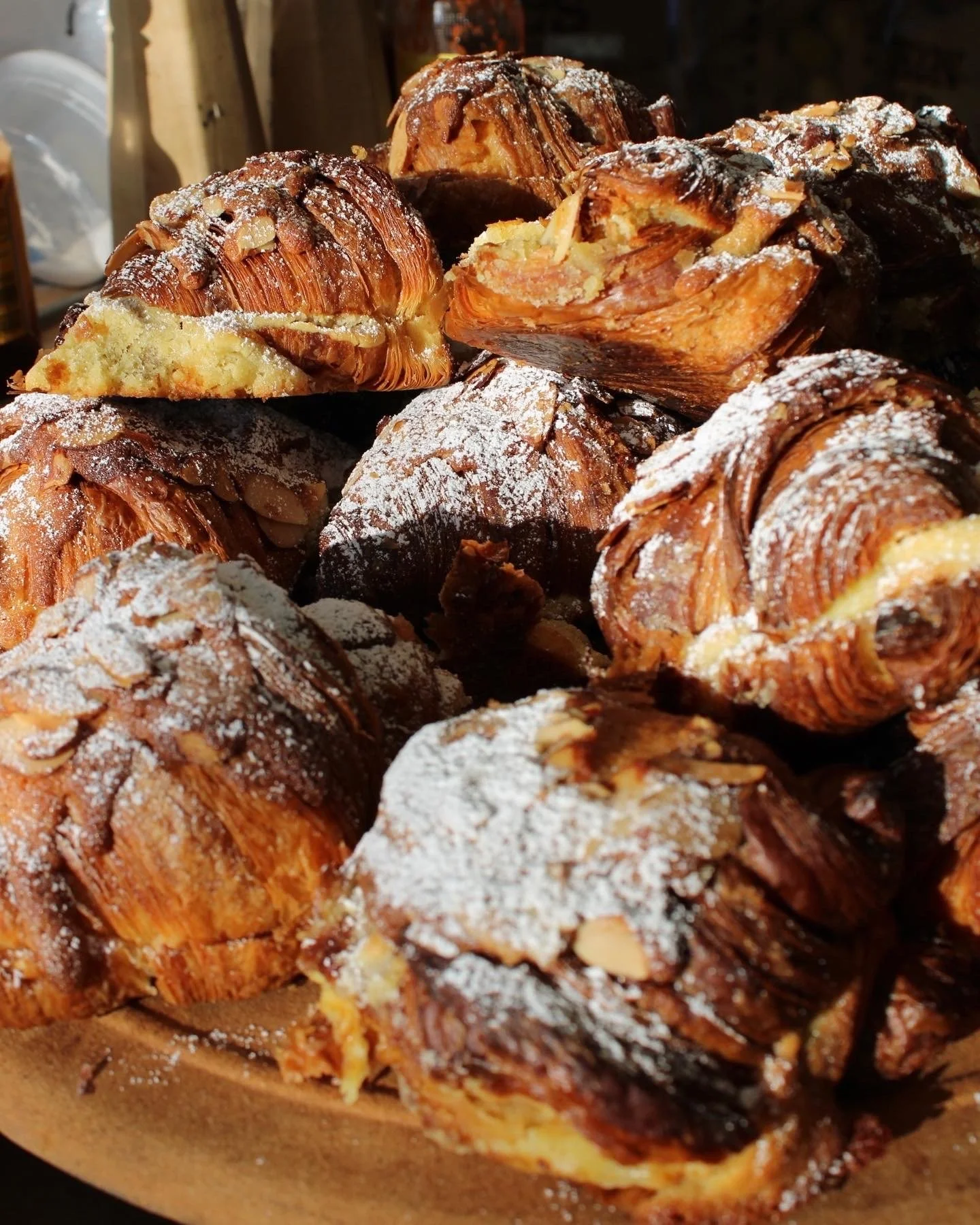 Close-up of assorted baked pastries topped with powdered sugar and sliced almonds.
