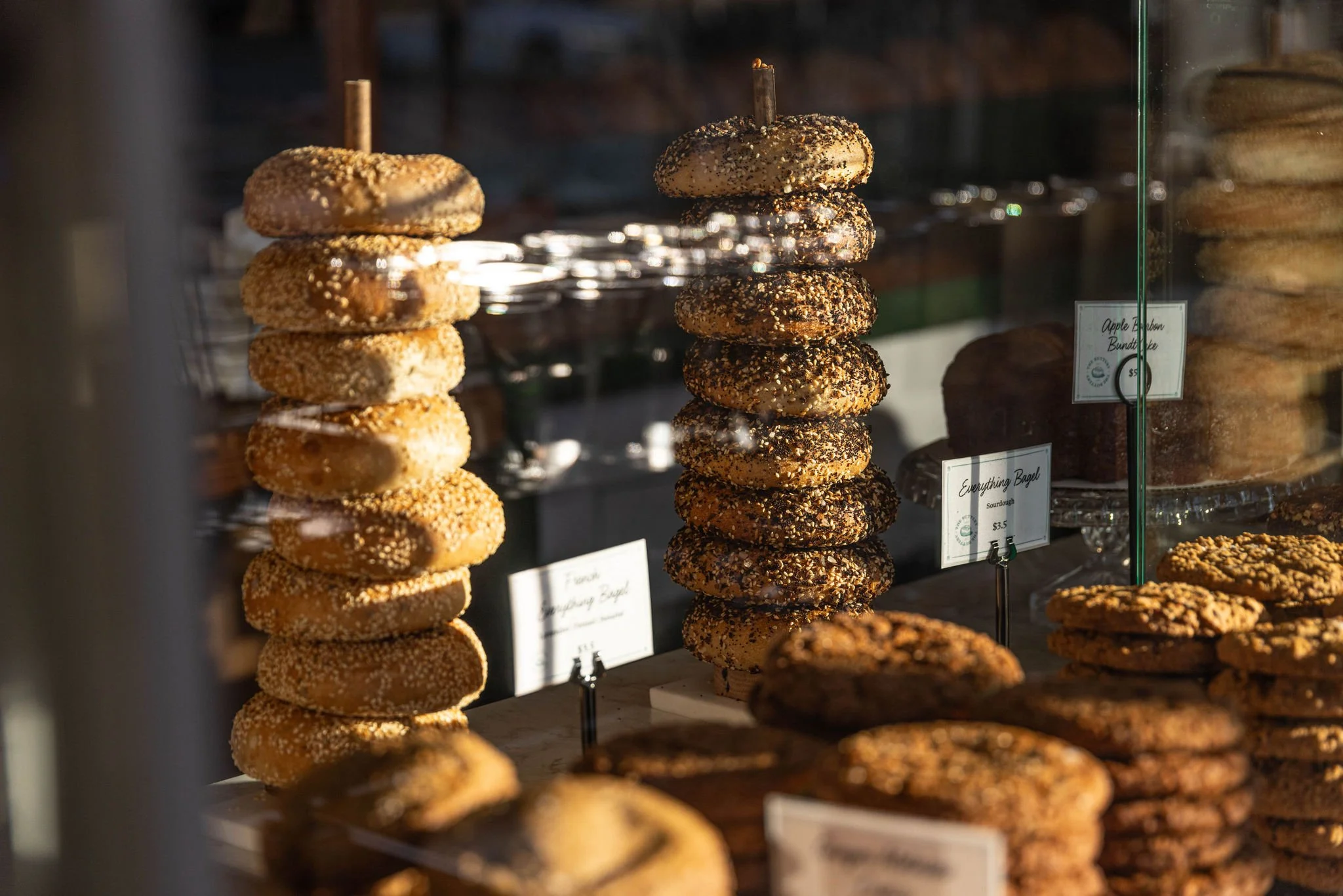 A display of stacked cookies in a bakery window, with various types covered in different toppings.