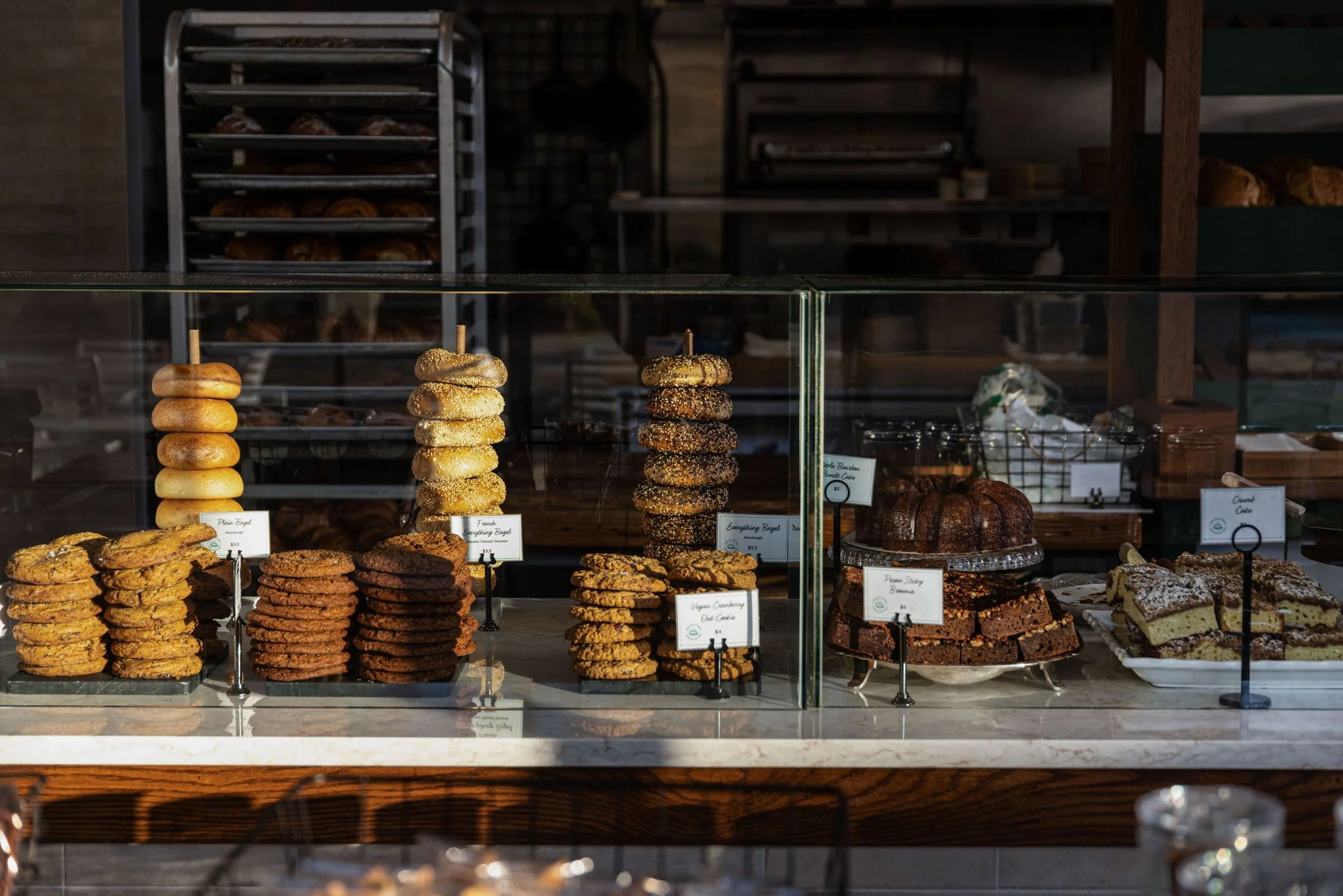Display case with assorted baked goods including cookies, bagels, and brownies in a bakery.